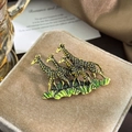 Detailed shot of enamel giraffe brooch with gold finish on velvet jewelry box - Gold