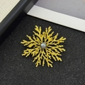 Dettaglio di una spilla a fiocco di neve dorata con perla grigia su sfondo nero lucido - Oro (Perla Grigia)