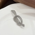 Dettaglio di una spilla vintage argentata a forma di nodo di corda con trama a spirale - Argento