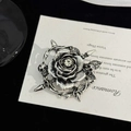 Detailaufnahme der Gothic-Brosche mit Totenkopf und Rose auf schwarzem Samthintergrund - Silber