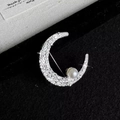 Elegant silver crescent moon brooch with shimmering crystals and a white pearl accent - Silver