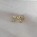 Detail of a golden bow brooch inlaid with clear rhinestones on pink silk fabric - Gold