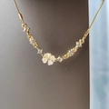 Macro-opname van een goudkleurige ketting met witte bloemblaadjes en strass-hart - Bloem / Goud