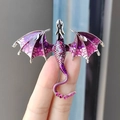 Spilla a forma di drago in smalto viola con strass scintillanti tenuta in mano - Viola
