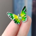 Spilla a farfalla vintage in smalto verde con gemma di smeraldo, mostrata sul polpastrello - Farfalla Piccola Verde