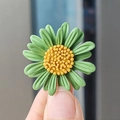 Broche de margarita verde con pétalos de resina y centro amarillo en la mano - Verde