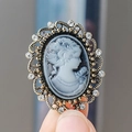Broche camafeo vintage de estilo victoriano con cristales sostenido en la mano - Gris