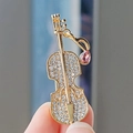 Macro detail of a violin brooch with gold plating and sparkling crystals held by hand - Golden Violin Pink Rhinestone Style (XZ0265-26)