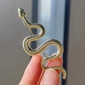 Broche de serpiente dorada con escamas texturizadas mostrado en mano para ver el detalle - Dorado