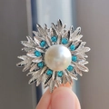 Elegante spilla a fiore con perla, cristalli blu e petali argentati tra le dita - Argento Blu Lago