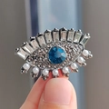Macro view of evil eye brooch with blue stone, crystal lashes and hanging pearl detail - Deep Blue Stone Style (XZ0376-1) / Blue