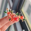 Elegant gold persimmon brooch with red berries and green enamel leaves held in hand - Red Persimmon Branch Style (XZ0435-1)