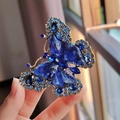 Detailansicht einer luxuriösen Schmetterlingsbrosche mit blauen Kristallen und Gold - Blau