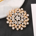 Goldene florale Sonnenbrosche mit weißen Kristallen auf minimalistischem Marmorhintergrund - Radialer Sonnenstrahl-Stil (BH07-Gold)