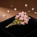 Vintage-Rosenstrauß-Brosche mit rosa Emaille-Blüten auf einer schwarzen Schmuckschatulle - Rosa Rosenstrauß