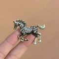 Elegant gold-tone horse brooch with white crystal inlay shown on a finger for scale - Enamel Steed Brooch White