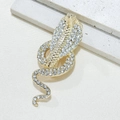 Funkelnde goldene Kobra-Brosche mit Strasssteinen auf weißem Marmorhintergrund - Voll Strass Kobra Stil / 16K Gold
