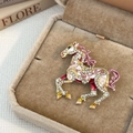 Detail view of a vintage pony brooch with crystal inlay and colorful enamel on a jewelry box - Pink
