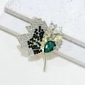Golden maple leaf brooch featuring emerald green rhinestones and sparkling crystals - Gold/Green