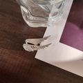 Macro detail of silver angel wing brooch with sparkling white zircons on wooden surface - Silver