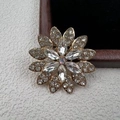 Dettaglio macro di un'elegante spilla a fiore con strass e petali in lega d'oro luccicanti - Stile Girasole Trasparente (XZ1183-1)