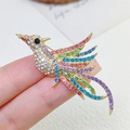 Vista macro de un broche de fénix colorido con alas doradas y cristales brillantes - Broche de Pájaro con Piedras Color Oro