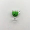 Macro detail of a miniature green bubble tea cup model with black pearls and tiny handle - Matcha Green