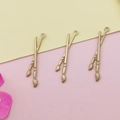 Primer plano de dijes de pincel en oro mate para crear joyas artesanales DIY - Pincel de escritura