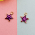Close-up of star pendants with purple enamel inlay and gold-tone beaded metal edges - Purple Celestial Star