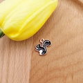 Macro detail of a squirrel charm with rose gold edges and black-white enamel for DIY jewelry - Squirrel