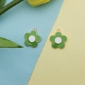 Detail of two green enamel plumeria charms with gold plating on a floral background - Green