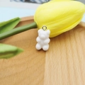 Macro shot of a white resin gummy bear charm with silver loop on a wooden tray - Solid White