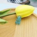 Close-up of a blue gummy bear resin charm with metal loop on a rustic wooden tray - Jelly Blue