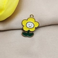 Dettaglio del ciondolo a forma di girasole in lega dorata con viso sorridente e smalto giallo - Giallo