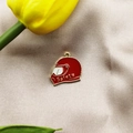 Macro shot of a red and gold mini motorcycle helmet pendant on beige silk fabric - Red Helmet