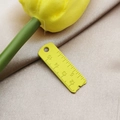 Detail of yellow ruler-shaped alloy pendant with scale markers on champagne satin fabric - Yellow