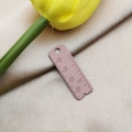 Detailed macro view of a matte dusty pink ruler pendant with precise engraved scale markings - Pink