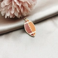 Detail of rugby-shaped enamel alloy pendant with golden edges on satin fabric background - Rugby Ball Shape / Rugby Ball