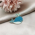 Detailed macro of a dark blue whale alloy enamel pendant on soft silk with floral decor - Whale