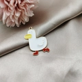 Close-up of a cartoon duck alloy pendant with colorful enamel on beige silk fabric - Duck