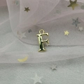 Détail d'un pendentif lettre F dorée pour création de bijoux DIY sur tissu en maille douce - Lettre F