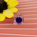 Dettaglio pendente cubo in resina trasparente con pallina viola e gancio dorato - Stile Cubo con Pom Pon / Viola