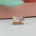 Detailed close-up of a pink enamel sewing machine charm with gold plating and rhinestones - Pink