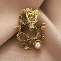 Gouden Chinese draak broche met strass steentjes en een paarse parel op zijden stof - Goud