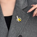 Broche creativo de plátano con esmalte amarillo y cristales brillantes en un abrigo gris - Estilo de Plátano