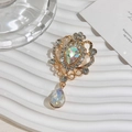 Close-up of golden vintage crown brooch with sparkling AB crystal teardrop pendants - AB Color