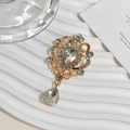 Close-up of golden vintage crystal brooch with teardrop rhinestone in elegant setting - White