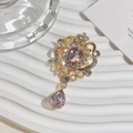 Close-up of golden vintage crystal brooch with teardrop rhinestones on white display - Light Pink