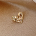 Elegante broche de corazón dorado con circonitas brillantes sobre fondo de seda marrón - Dorado