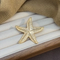 Vintage Seestern-Brosche in Gold mit Reliefstruktur auf cremefarbenem Samt - Gold
